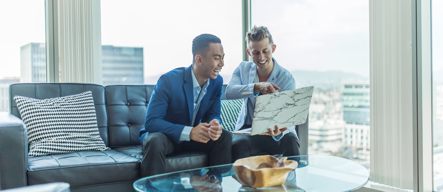 Business men sitting on sofa looking at laptop